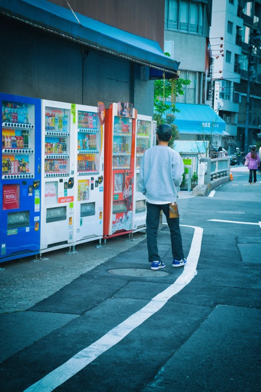 a young man looks at vending machines outside