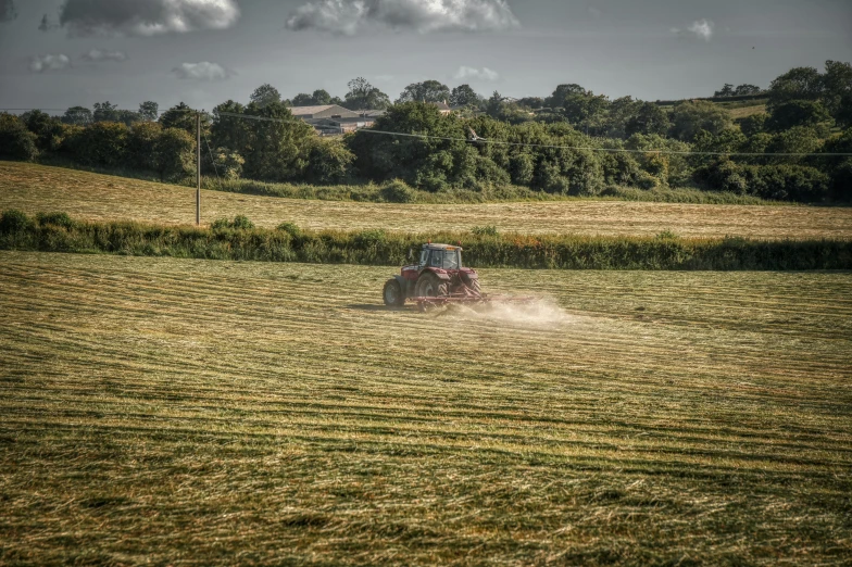 tractor with dust flying around in an open field