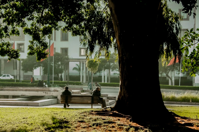 two people are sitting on a park bench and looking at the ground