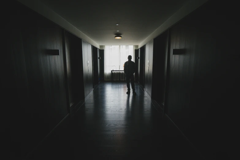 a dark hallway has doors to indicate the man is coming