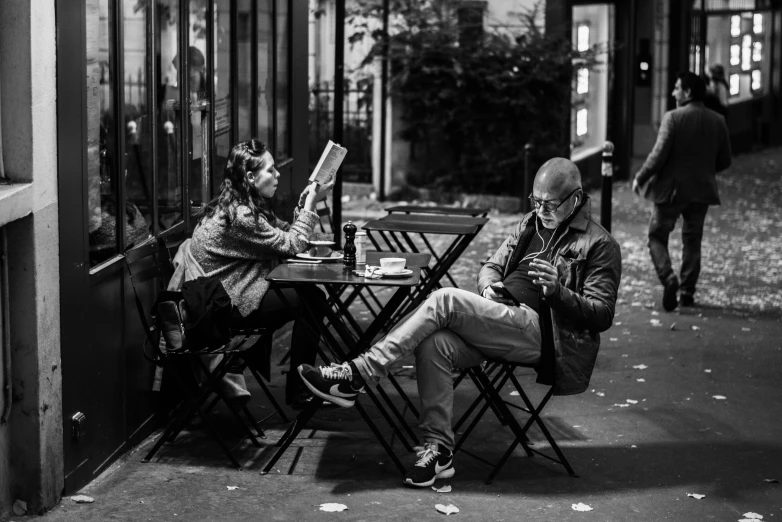 two people are sitting at a table on the sidewalk