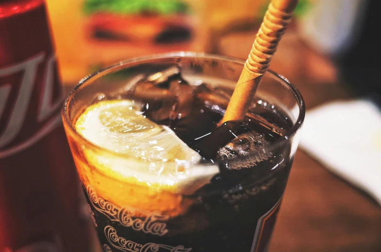 a glass filled with dark ice, cola and a straw