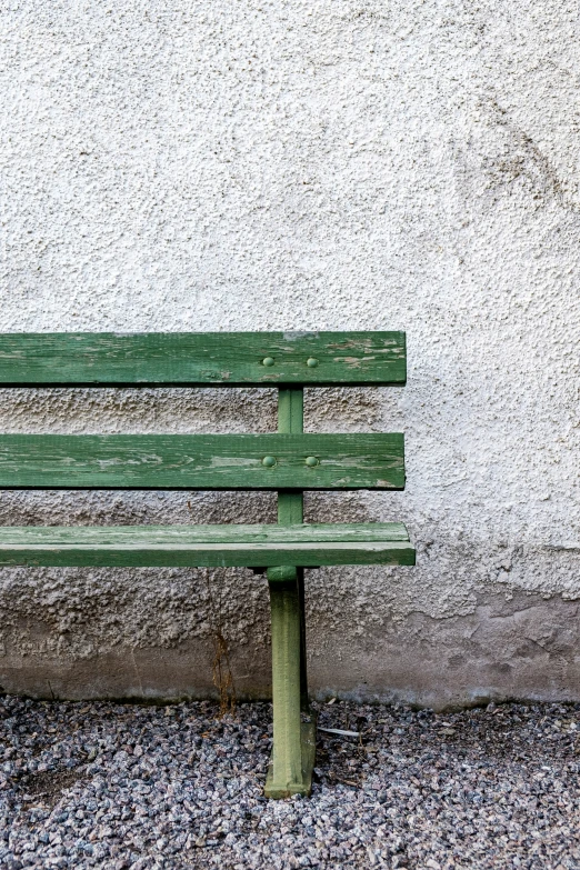 a wood bench next to a stucco wall