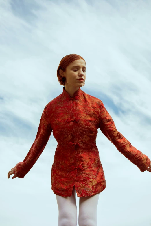 a woman wearing an orange top stands on a clear day