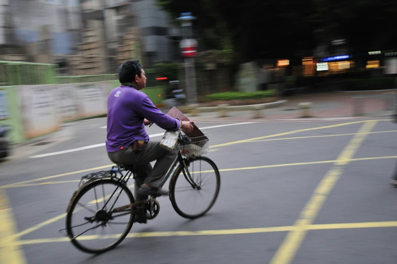 the man in the purple jacket is riding his bicycle down the street