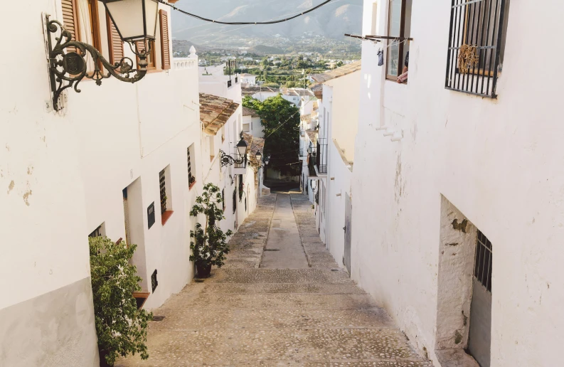 narrow alleyway between two white buildings with balconies and window frames