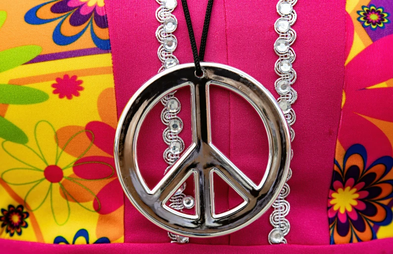 a peace symbol necklace hangs from a colorful dress