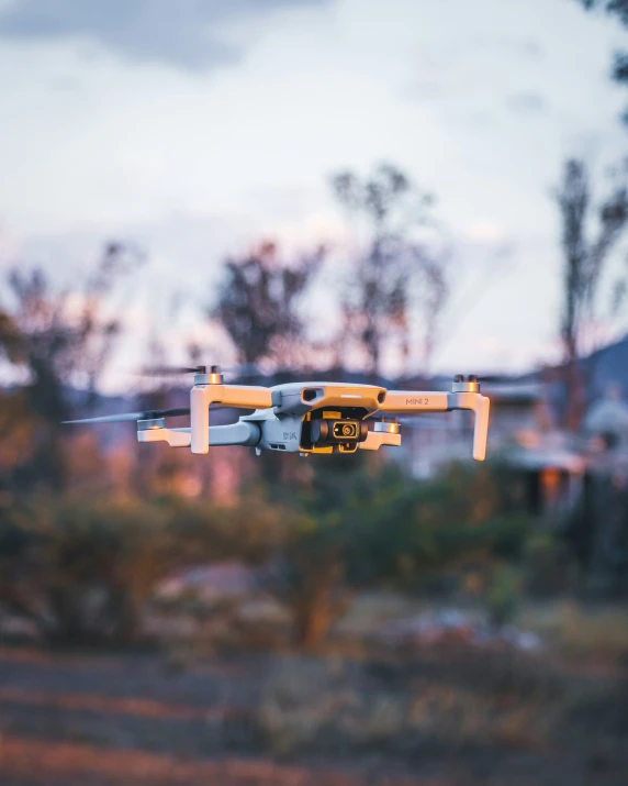 a close up of a yellow and grey unmanned flying in the air