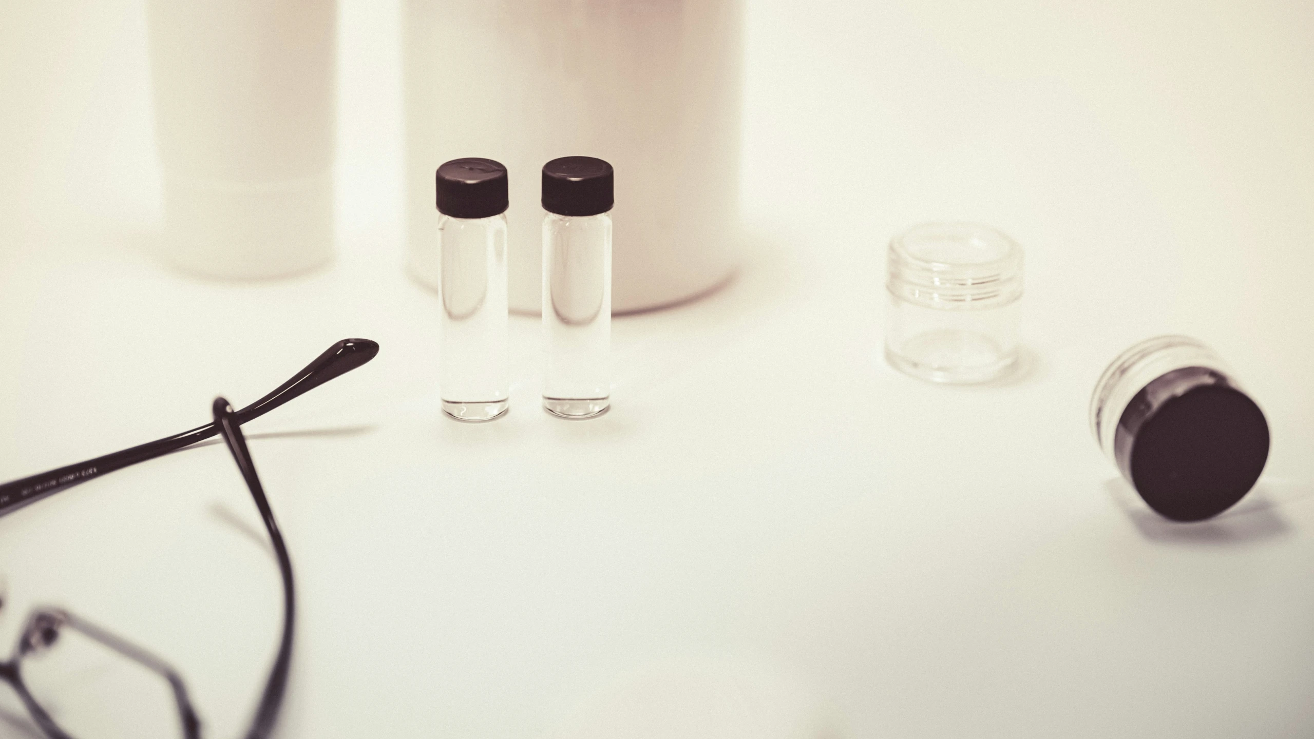 white jars, eye glasses and a pair of glasses sit on a table