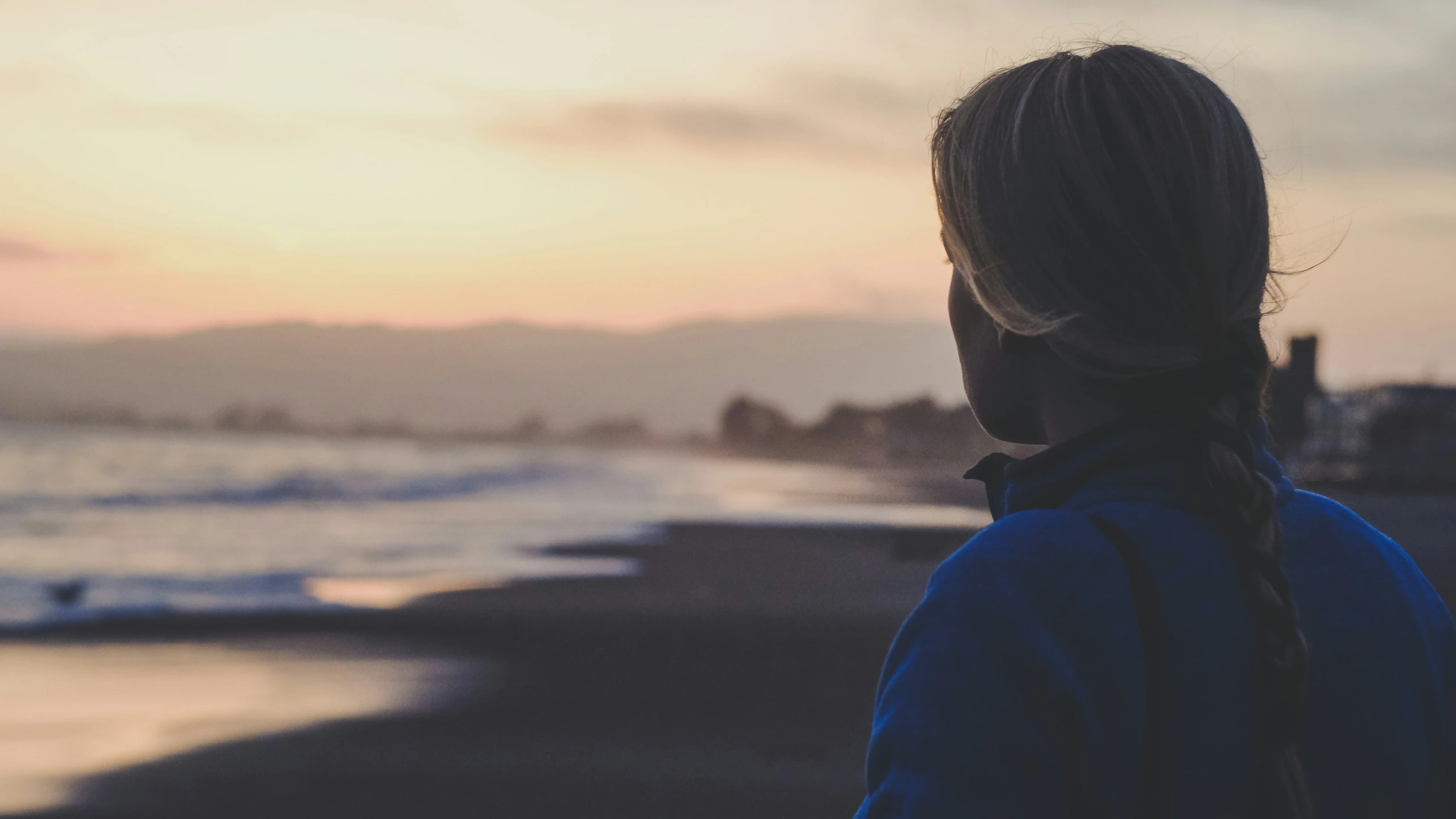 a person in a blue jacket standing near the ocean