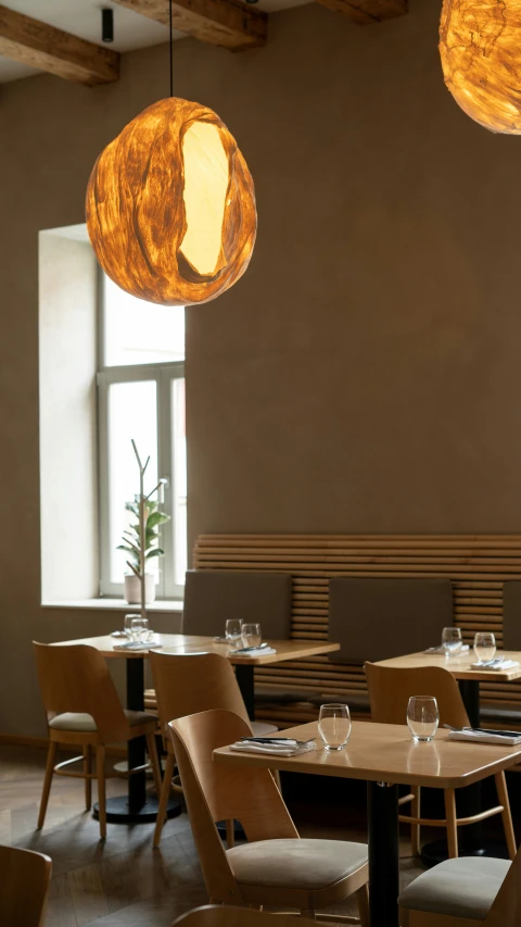 a restaurant with lots of tables with chairs, and lights hanging from the ceiling