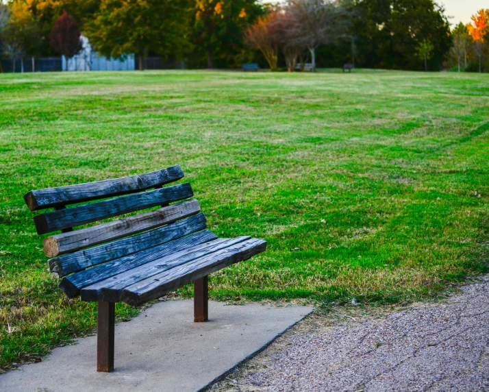 a wooden park bench sitting on top of a cement walkway