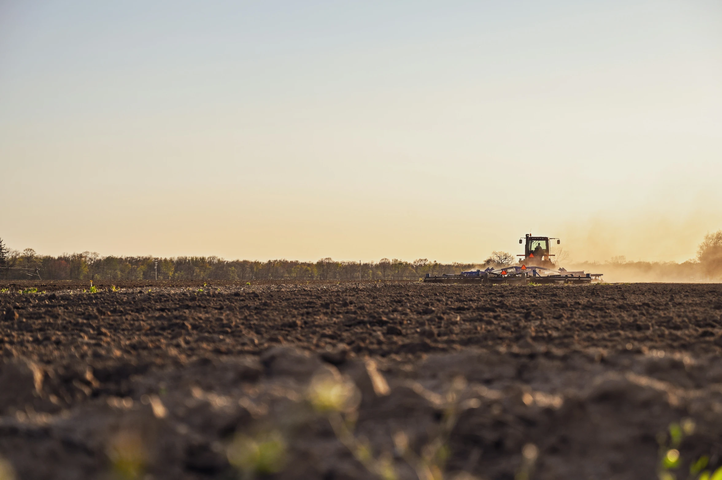 a tractor moves on a farm land during the sun rise