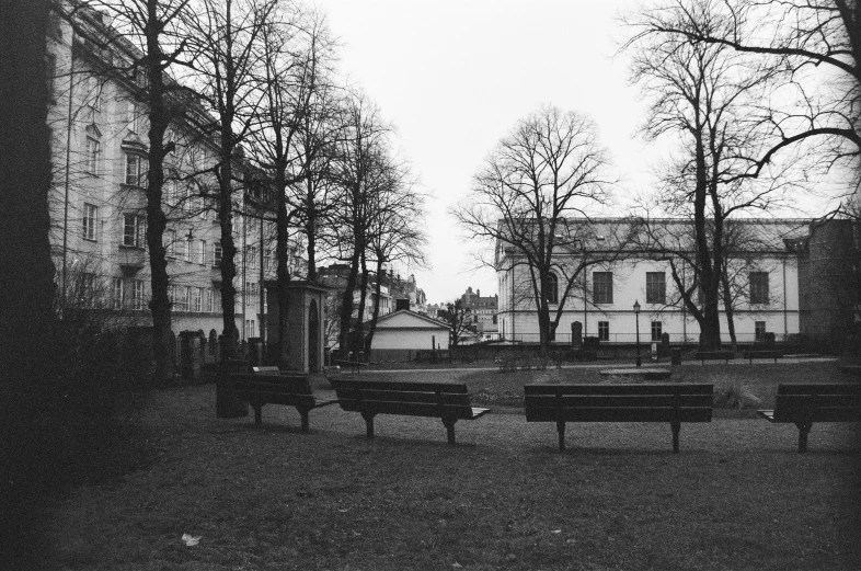 a group of park benches sit next to tall buildings