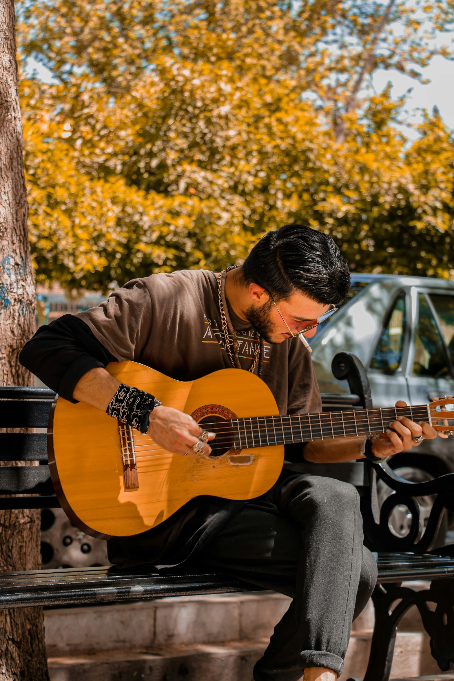 a man is sitting on a park bench playing an instrument