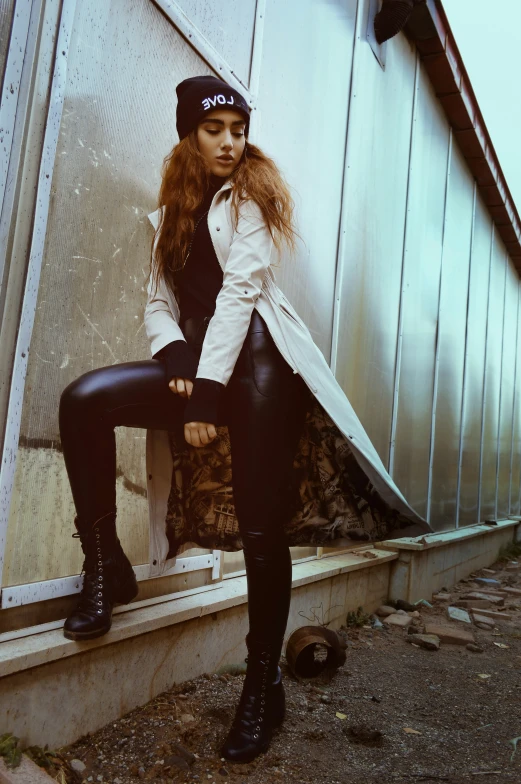 a woman in all black poses next to a building