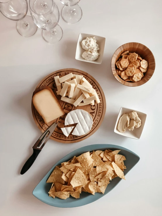 a plate with a bowl of chips, slices of cheese and ers