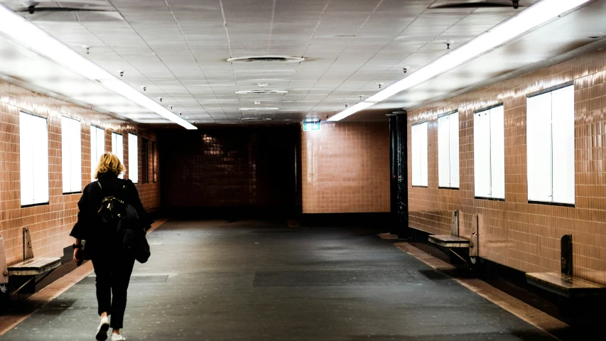 a person walks down the long hallway between two windows