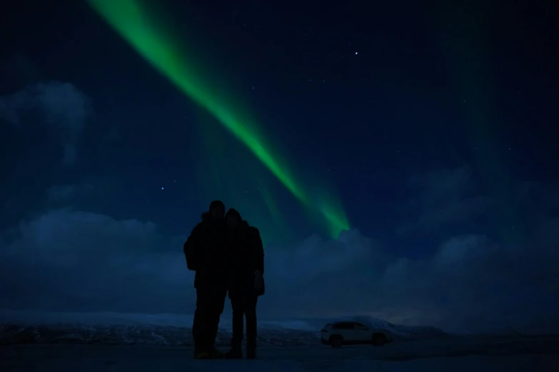 two people in the snow under an aurora bore