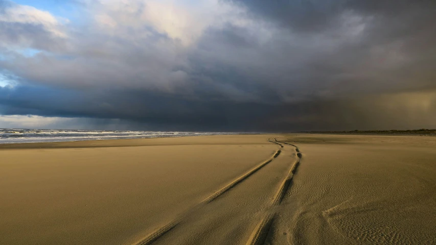 there are tracks in the sand as the sun rises