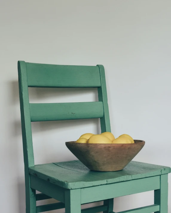 a wooden bowl sitting on top of a green chair