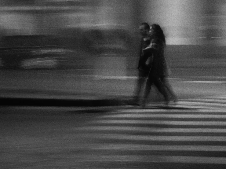 a blurry pograph of two people on the crosswalk