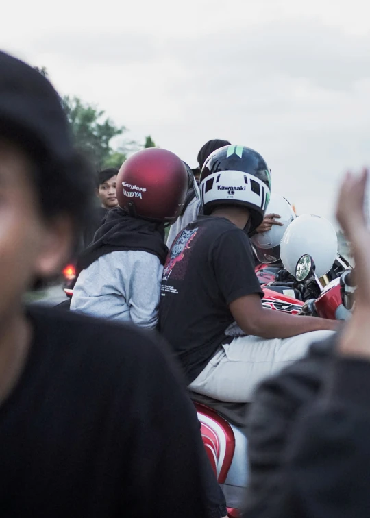 group of people with helmets sit on the back of a motorcycle