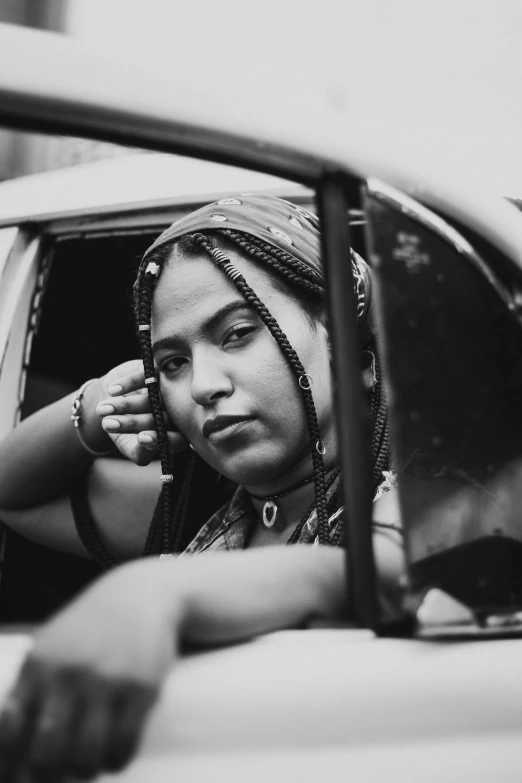 black and white po of woman in car holding hands to her ear