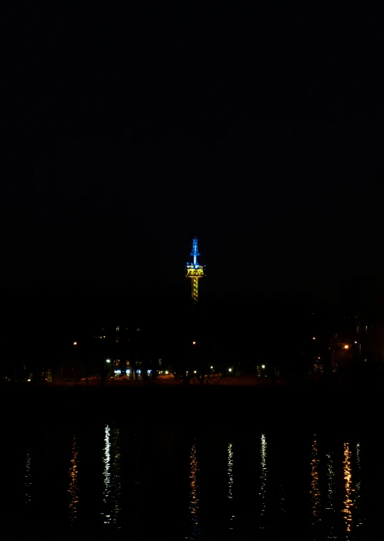 a view of the top of a building at night from a river with bright reflections