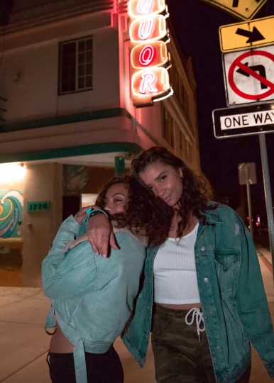 two young women in front of a light up sign