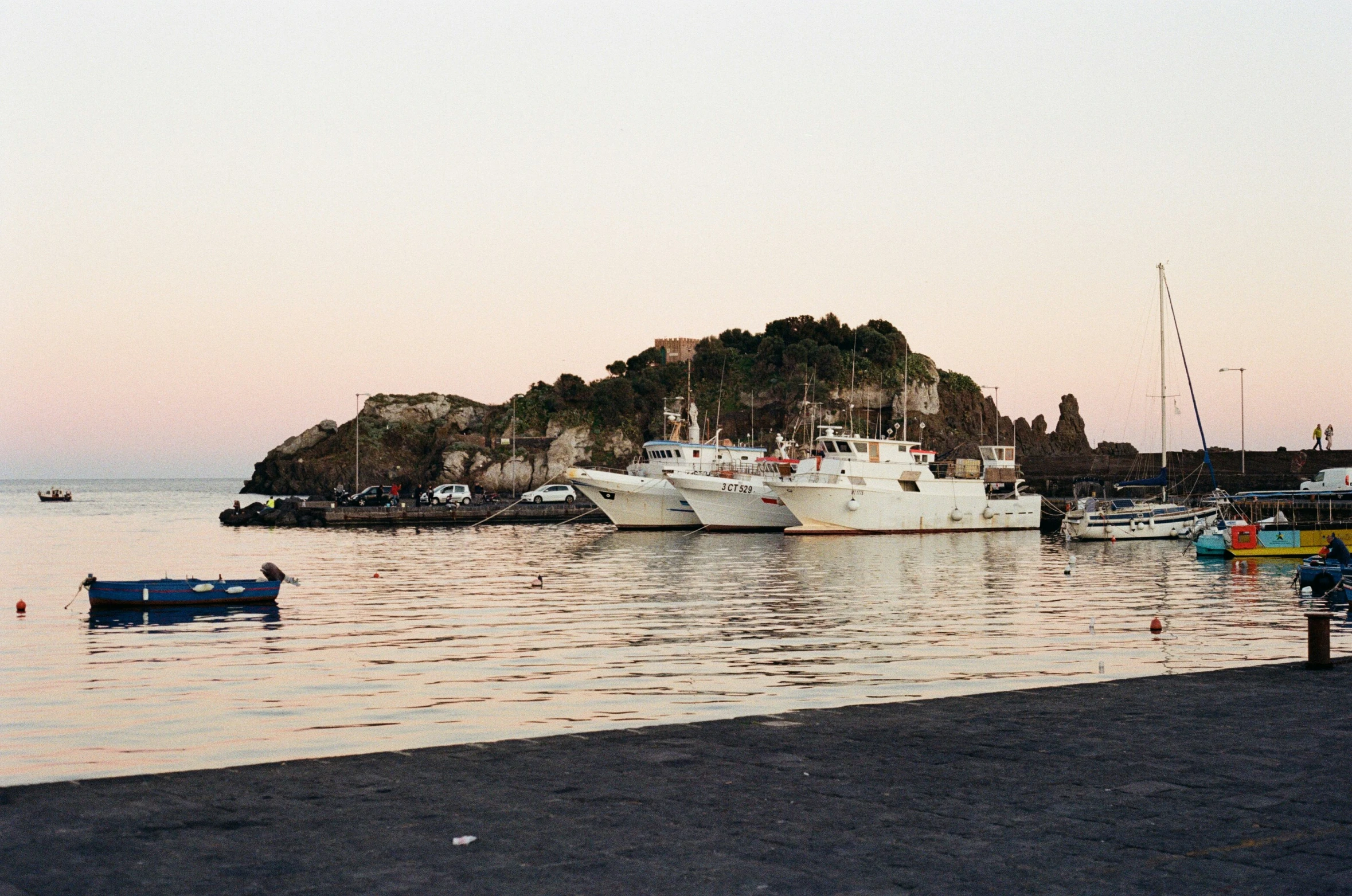 boats are lined up in a harbor with an island in the background