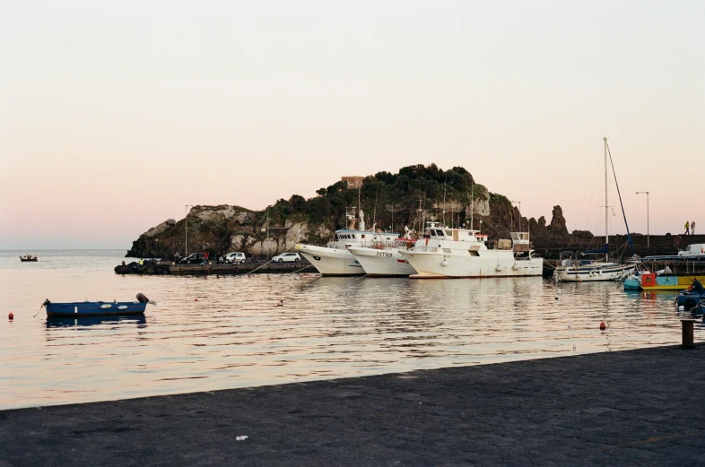 boats are lined up in a harbor with an island in the background