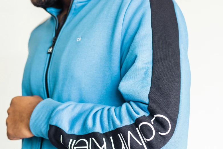 the jacket in sky blue features embroidered lettering and black piping