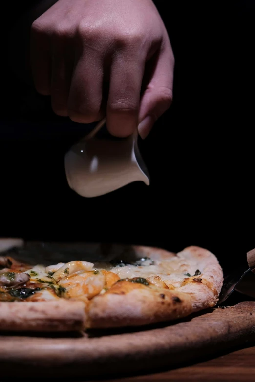 a person cuts into a pizza with a pair of serving utensils