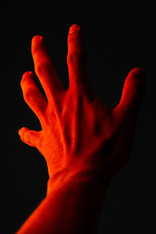 a red hand reaching towards the dark background