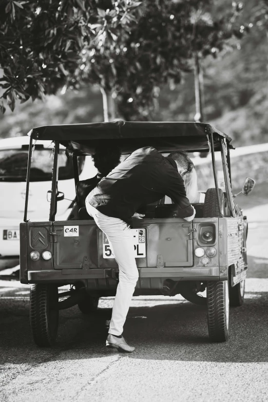 a man on the back of a jeep is bent over