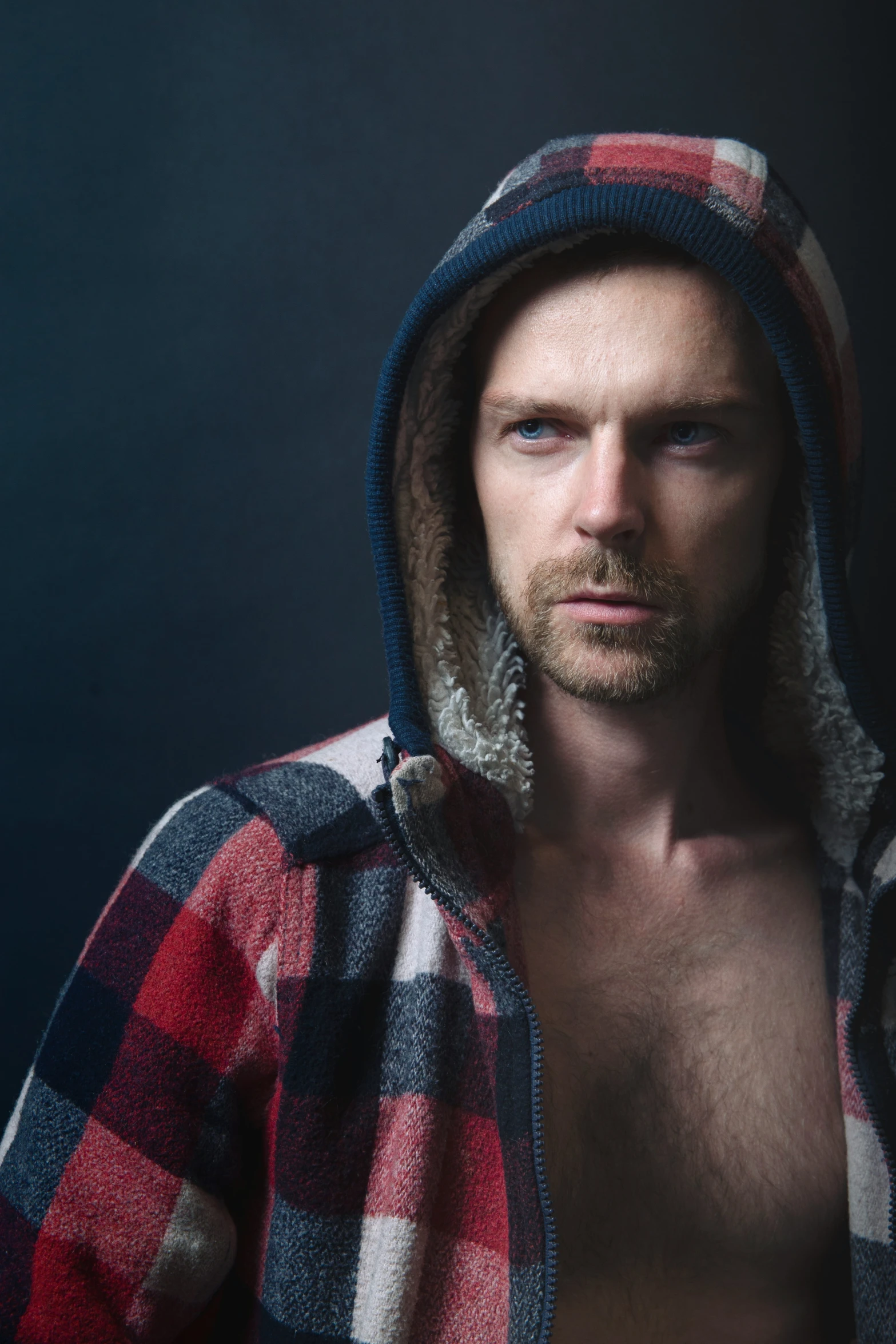 a shirtless young man in plaid sweater posing for camera