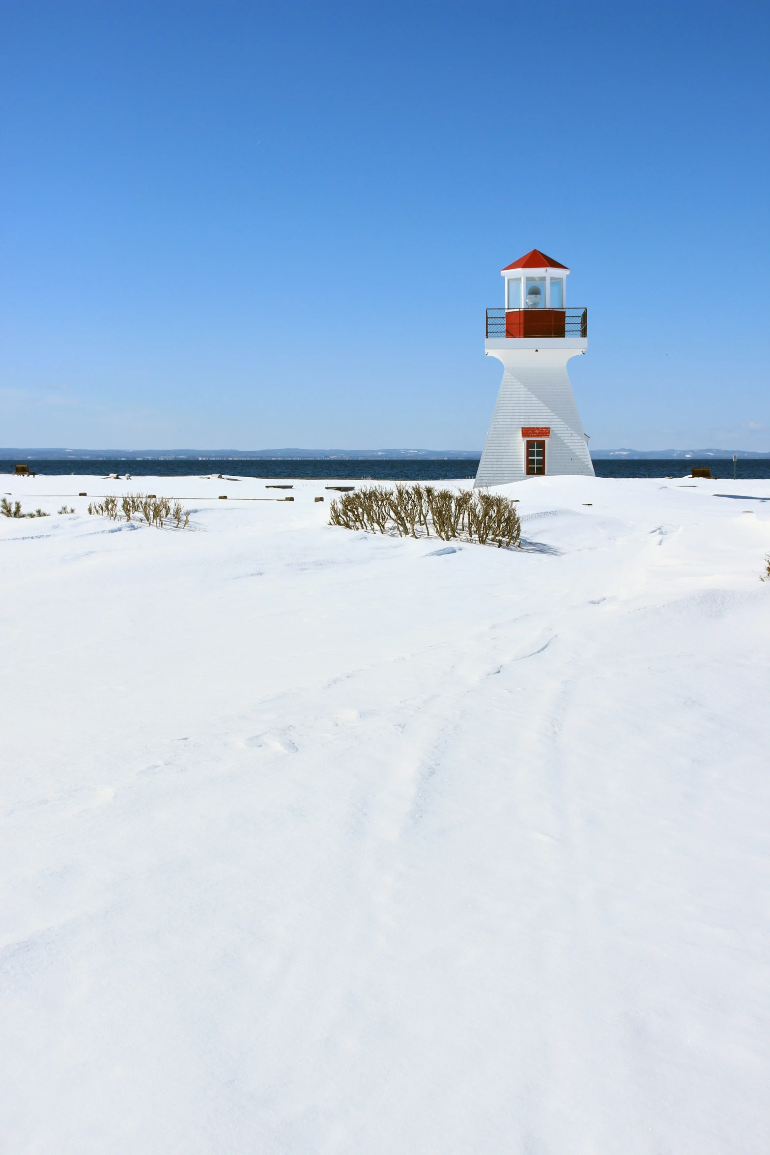 a white lighthouse is on a snowy island