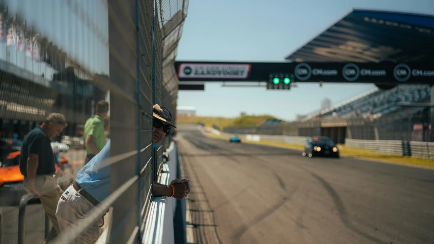 a person leaning against a fence at a track