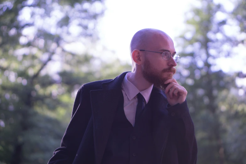 a man in glasses is standing outside wearing a suit