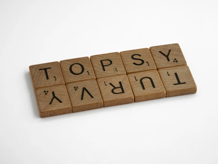 scrabbled word spelled on wooden tiles spelling the words topsy and normal