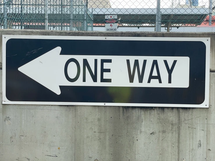 a one way sign mounted on the side of a wall