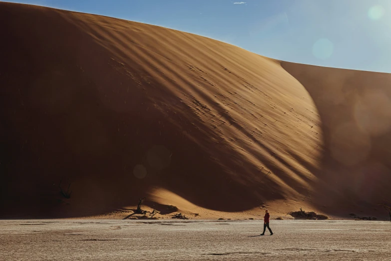 two people walking in a field near a large sand dune