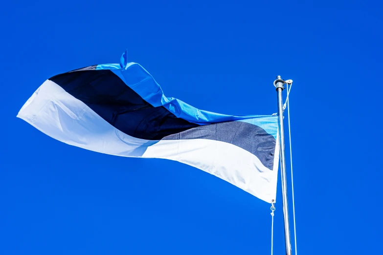 a large flag blowing in the wind on top of a blue sky