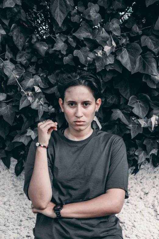 a woman in gray shirt sitting next to some plants