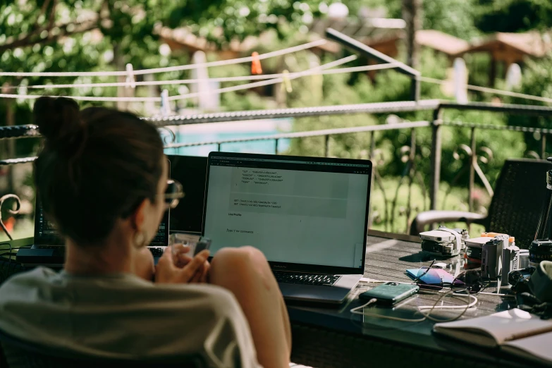 a woman sitting at a table with a laptop and a phone