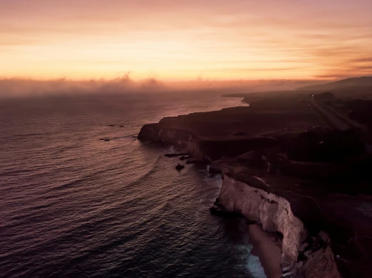 two surfers are surfing a wave off the coast of a cliff