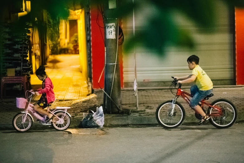 a boy and a girl riding bicycles on the street