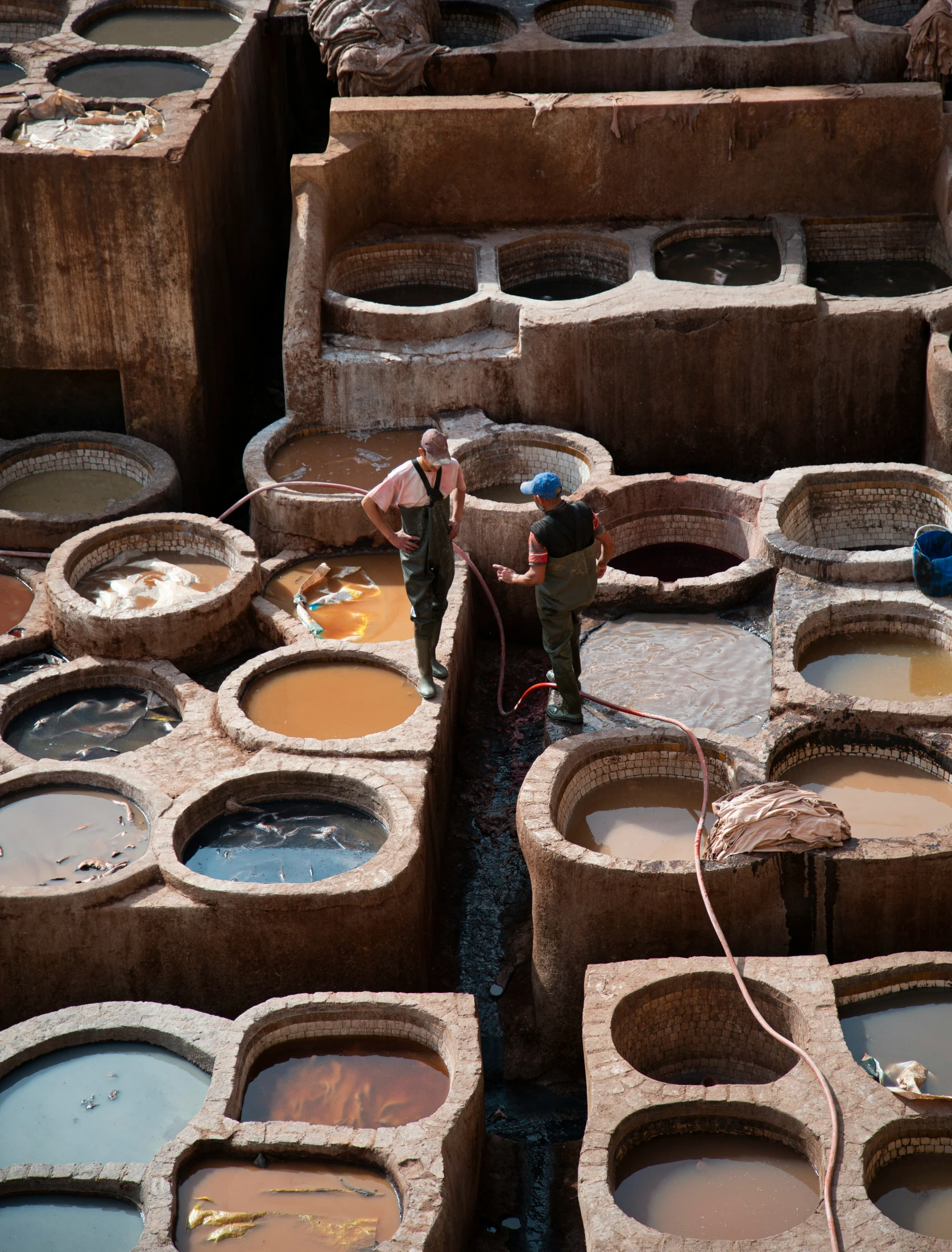 two men paint pot holes on cement with paintbrushes