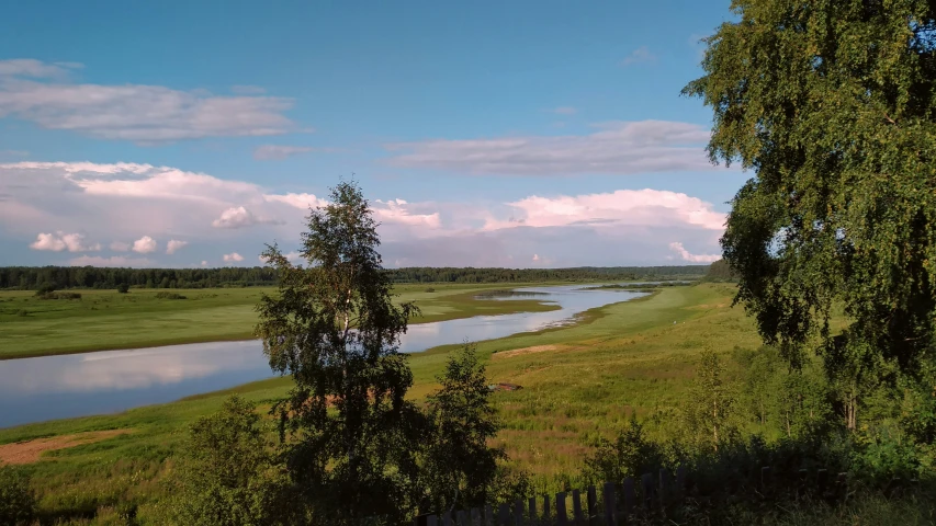 the river is flowing along the small grassy field